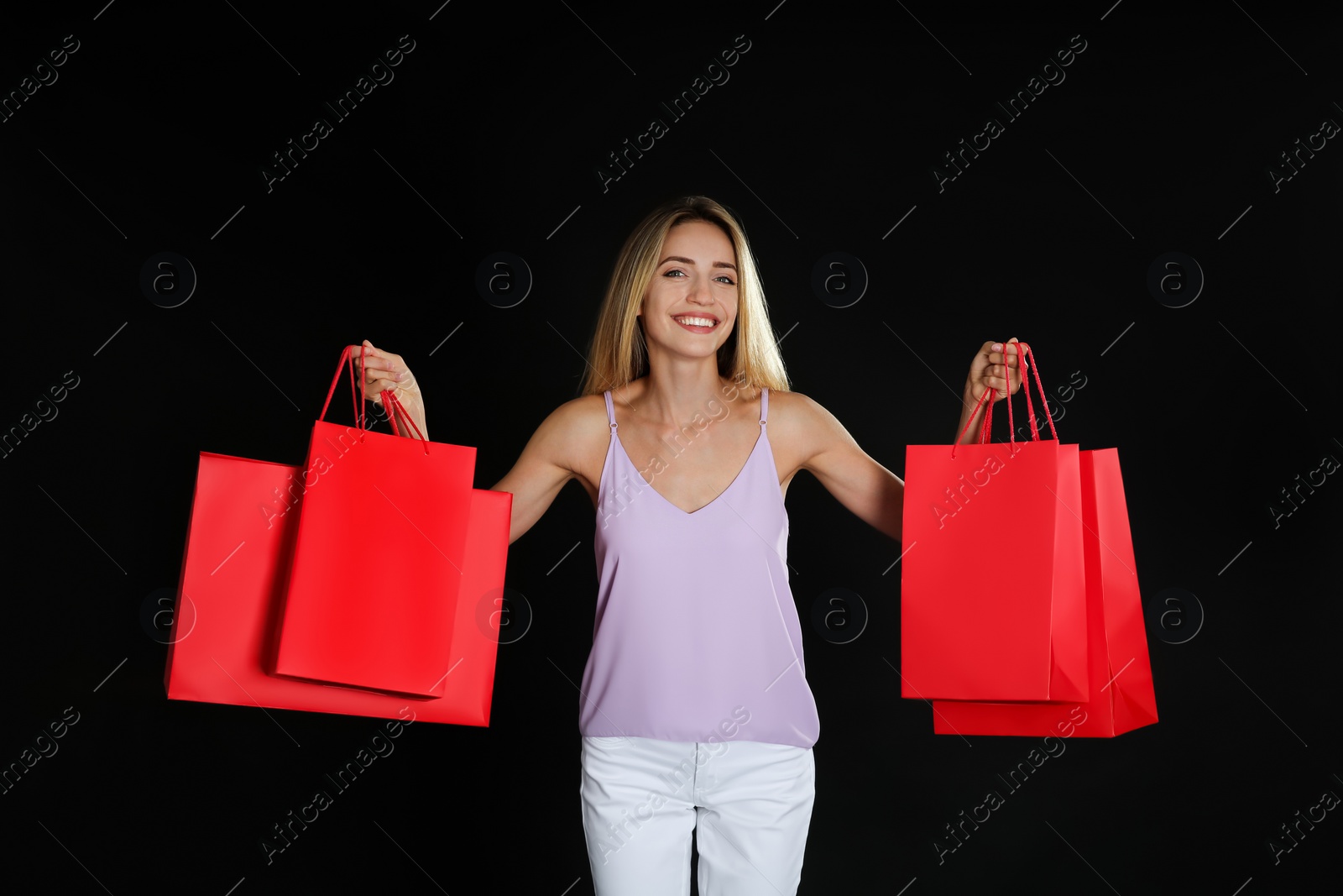 Photo of Happy young woman with shopping bags on dark background. Black Friday Sale