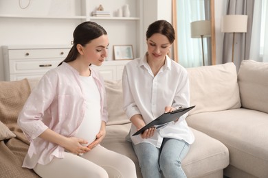 Doula working with pregnant woman on sofa at home. Preparation for child birth