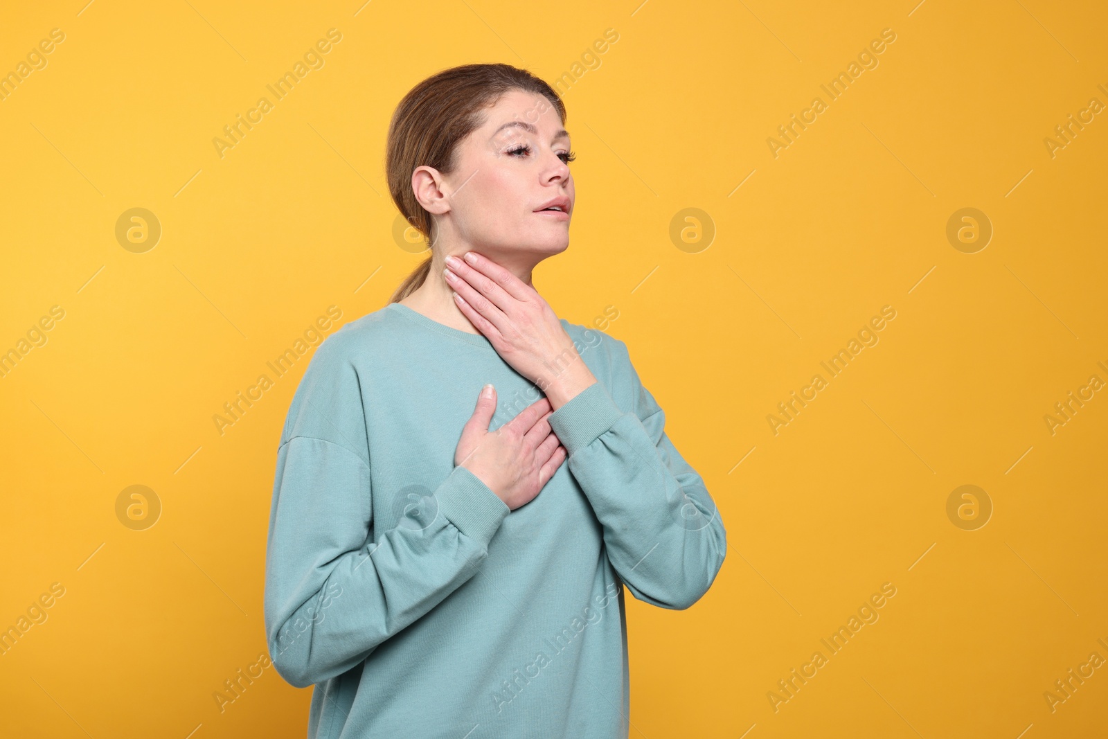 Photo of Woman suffering from sore throat on orange background