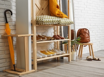 Photo of Stylish hallway interior with shoe rack near brick wall