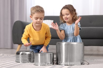 Little children pretending to play drums on pots at home