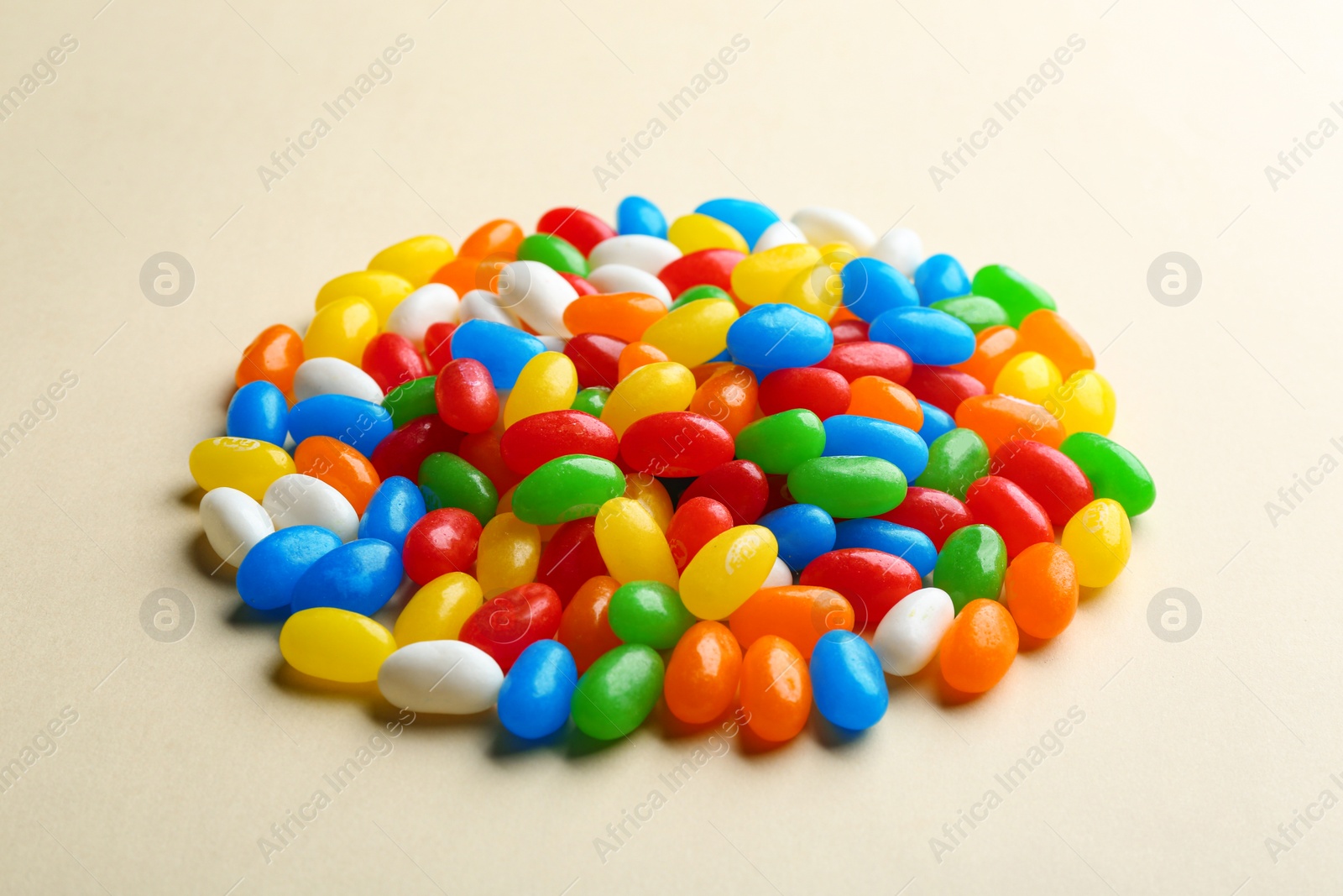 Photo of Pile of colorful jelly beans on beige background