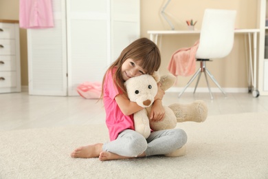 Cute little girl playing with teddy bear at home