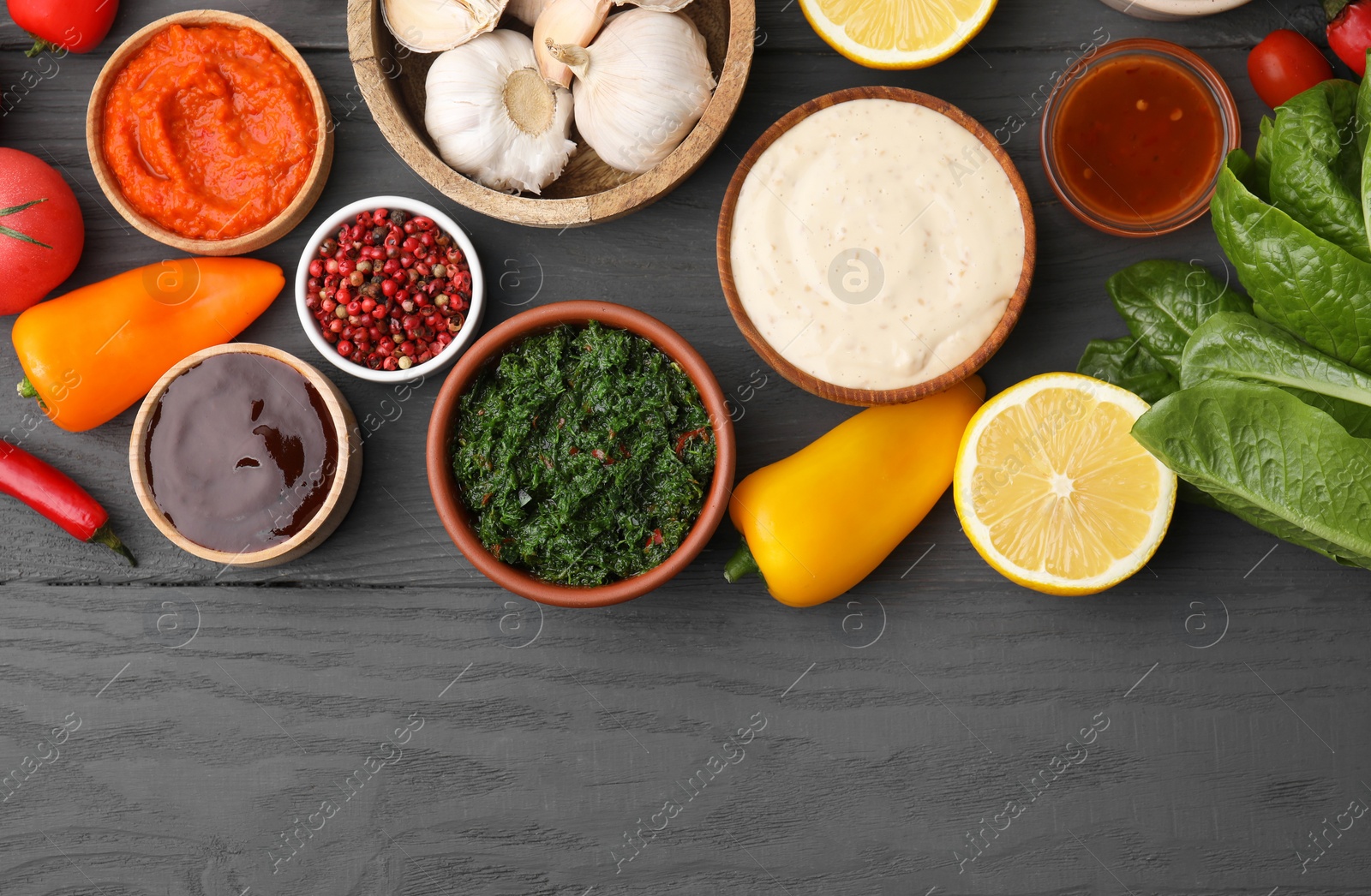 Photo of Different fresh marinades in bowls and ingredients on grey wooden table, flat lay. Space for text