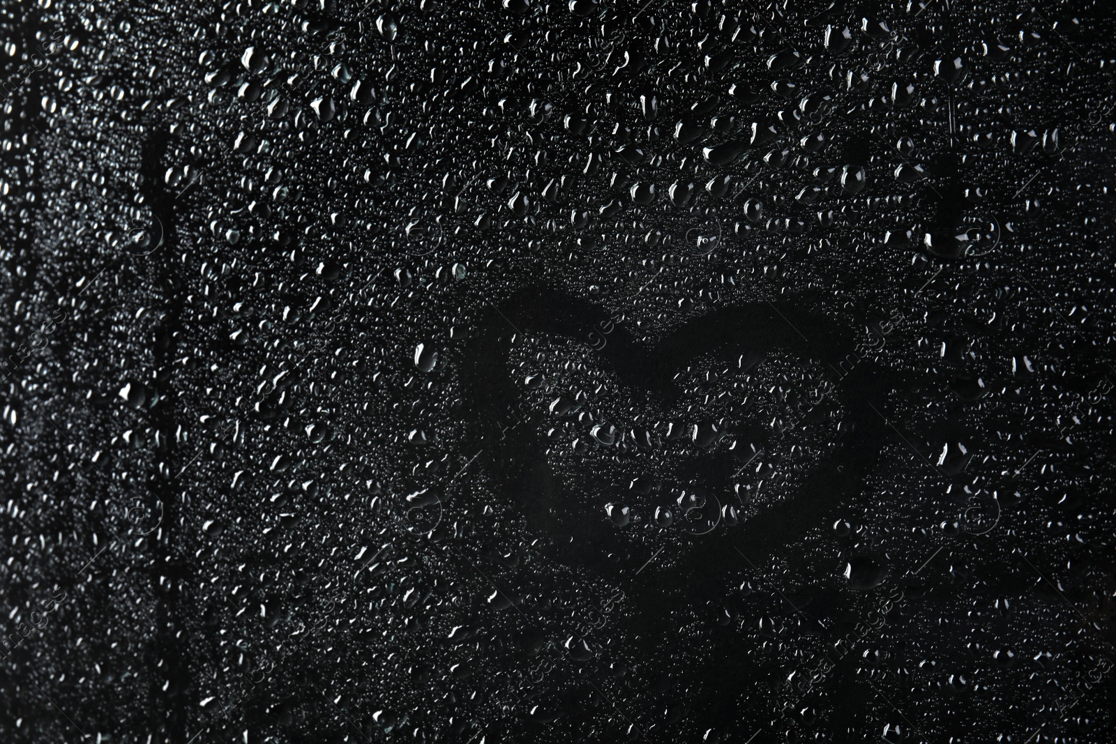 Photo of Glass with rain drops against dark background