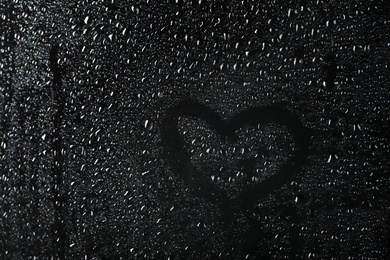 Photo of Glass with rain drops against dark background