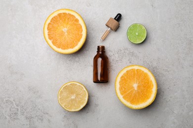 Photo of Bottle of citrus essential oil and fresh fruits on light table, flat lay