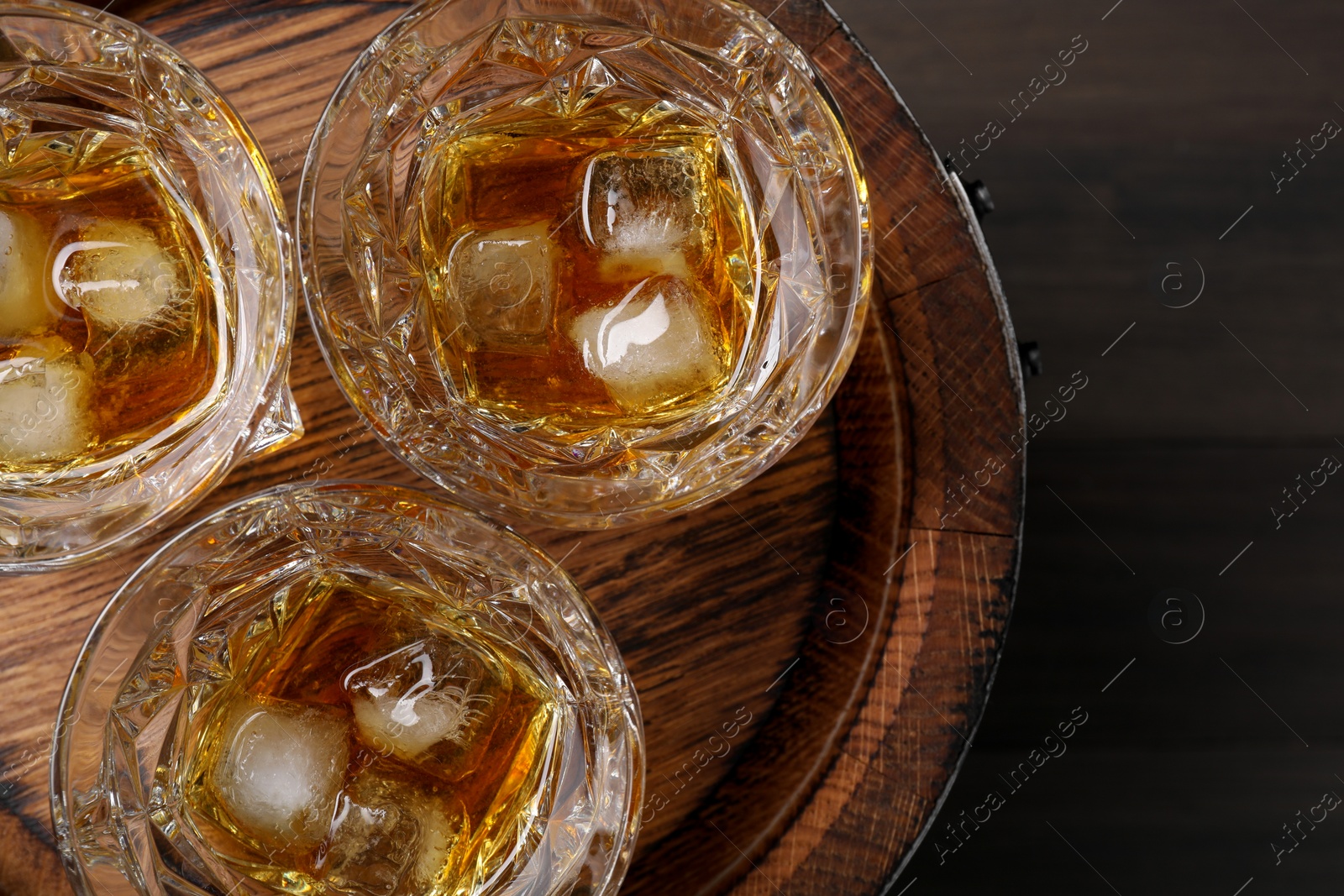 Photo of Tasty whiskey on wooden barrel, top view