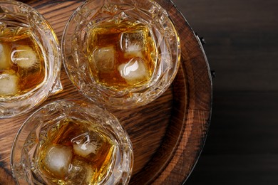 Photo of Tasty whiskey on wooden barrel, top view