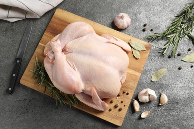 Photo of Fresh raw chicken with spices and knife on grey textured table, flat lay