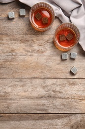 Photo of Glasses with liquor and whiskey stones on wooden background, top view