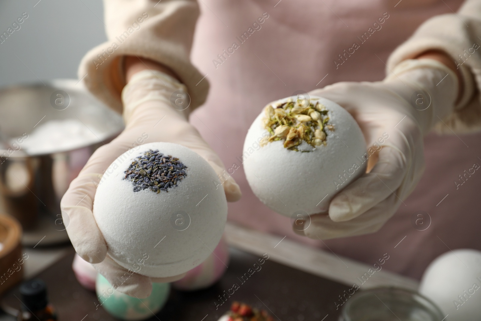 Photo of Woman in gloves with self made bath bombs at table, closeup