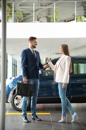 Photo of Salesperson giving car key to man in auto dealership