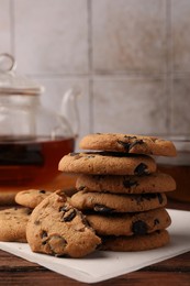 Stack of delicious chocolate chip cookies and tea on wooden table