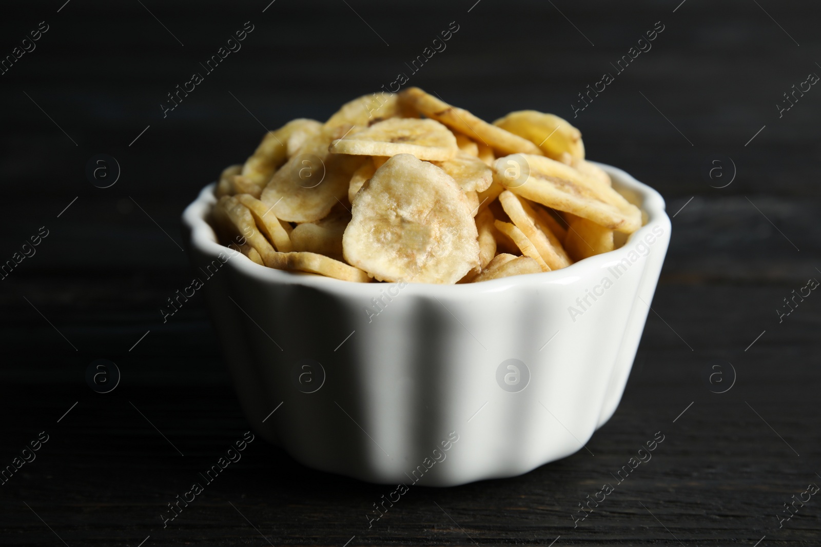 Photo of Bowl with sweet banana slices on wooden  table. Dried fruit as healthy snack