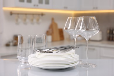 Photo of Set of clean dishware, glasses and cutlery on table in kitchen