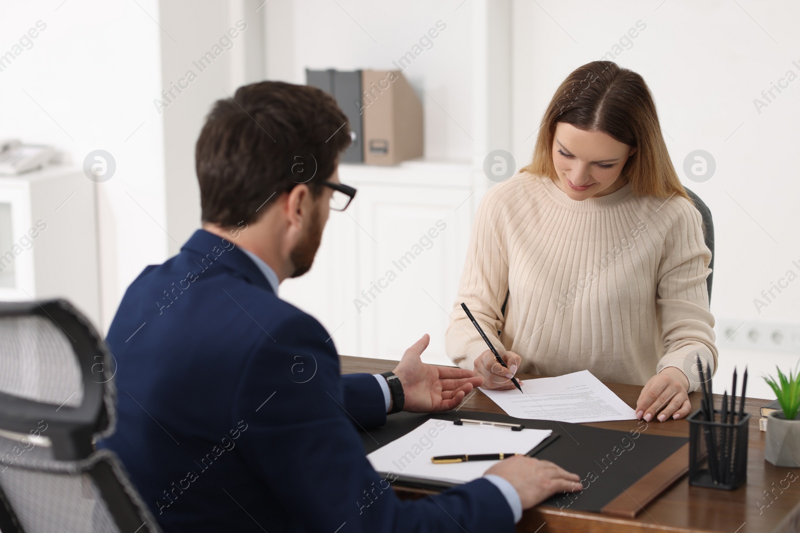 Photo of Woman signing document while having meeting with lawyer in office