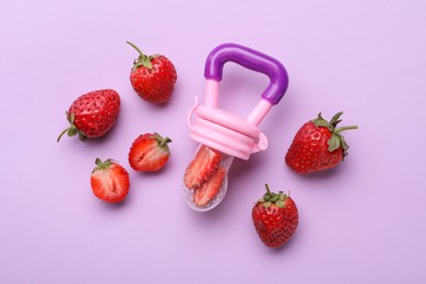 Photo of Nibbler with fresh strawberries on violet background, flat lay. Baby feeder