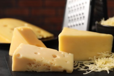 Photo of Grated and cut cheese on black table, closeup