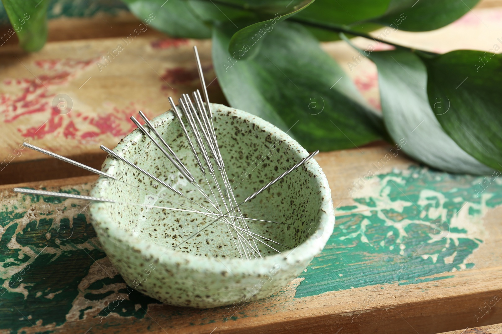 Photo of Bowl with acupuncture needles on wooden table, closeup. Space for text