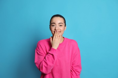 Photo of Beautiful young woman laughing on light blue background. Funny joke