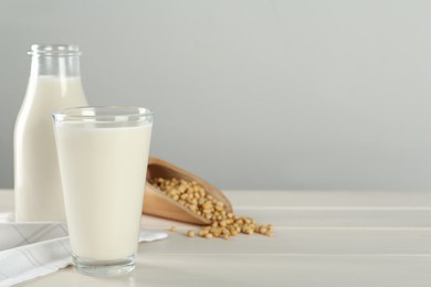 Photo of Fresh soy milk and grains on white wooden table. Space for text