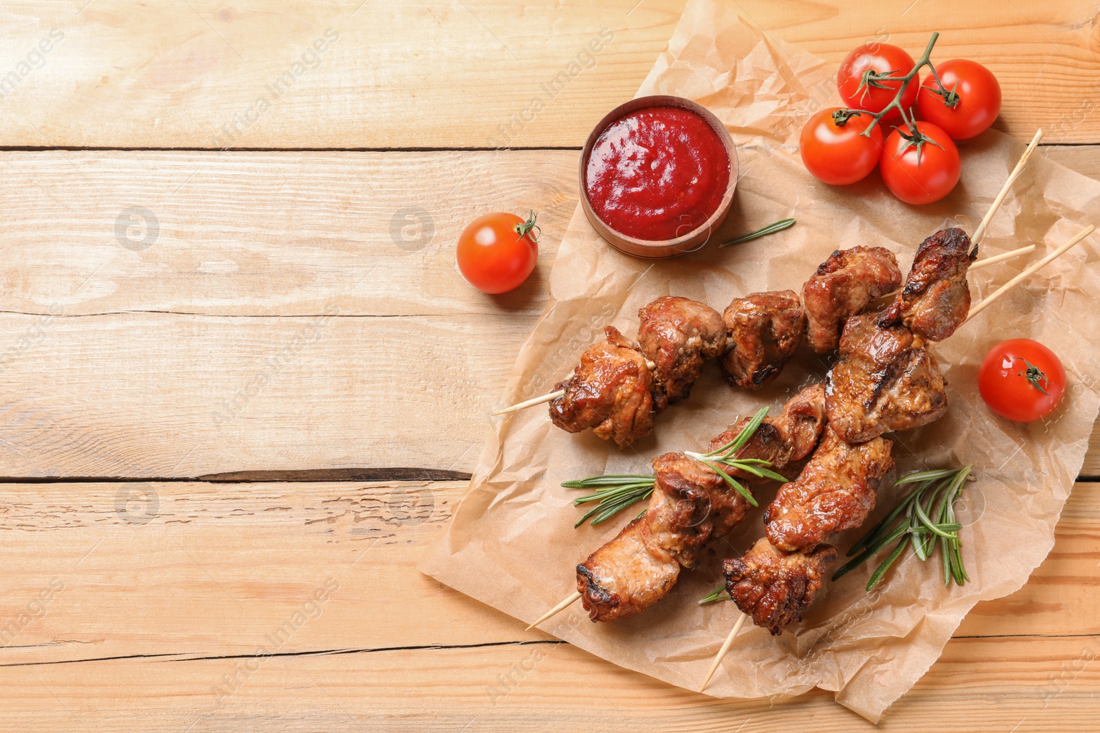 Photo of Delicious barbecued meat served with sauce and garnish on wooden background, top view. Space for text