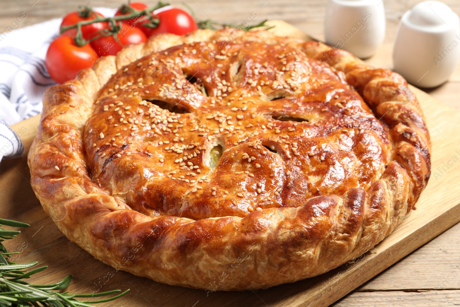 Photo of Tasty homemade pie, rosemary and tomatoes on wooden table