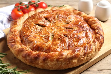 Tasty homemade pie, rosemary and tomatoes on wooden table