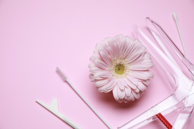 Photo of Gynecological treatment. Sterile speculum and gerbera flower on pink background, flat lay. Space for text