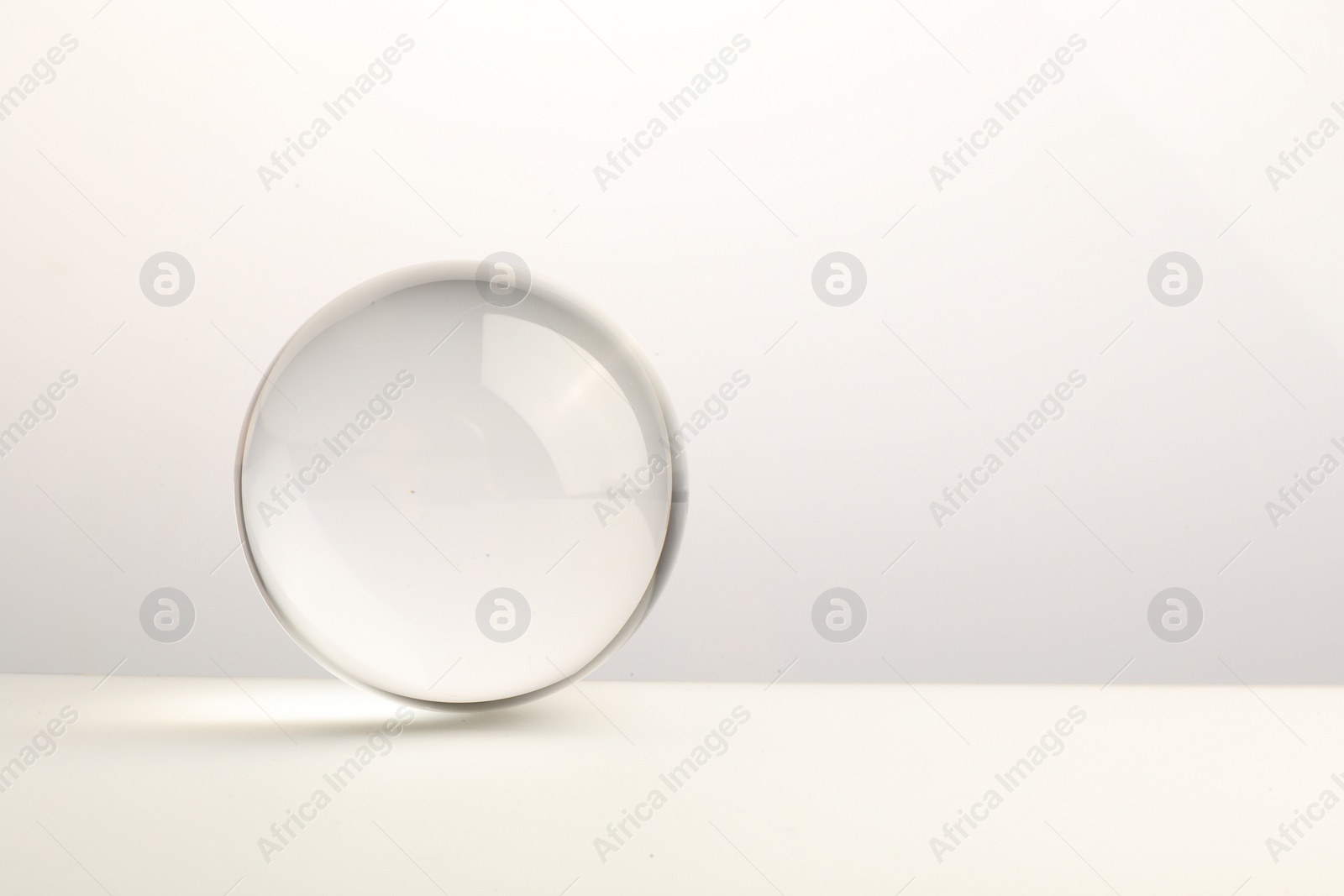 Photo of Transparent glass ball on white background. Space for text