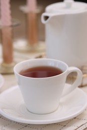 Cup of tea and teapot on white table, closeup