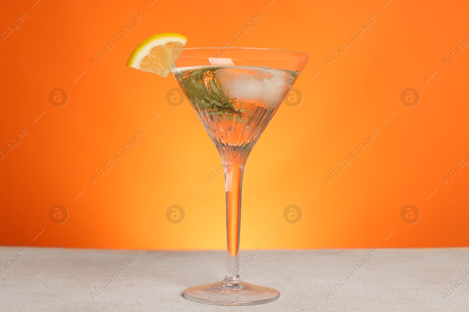 Photo of Martini glass of refreshing cocktail with lemon slice and rosemary on light grey table