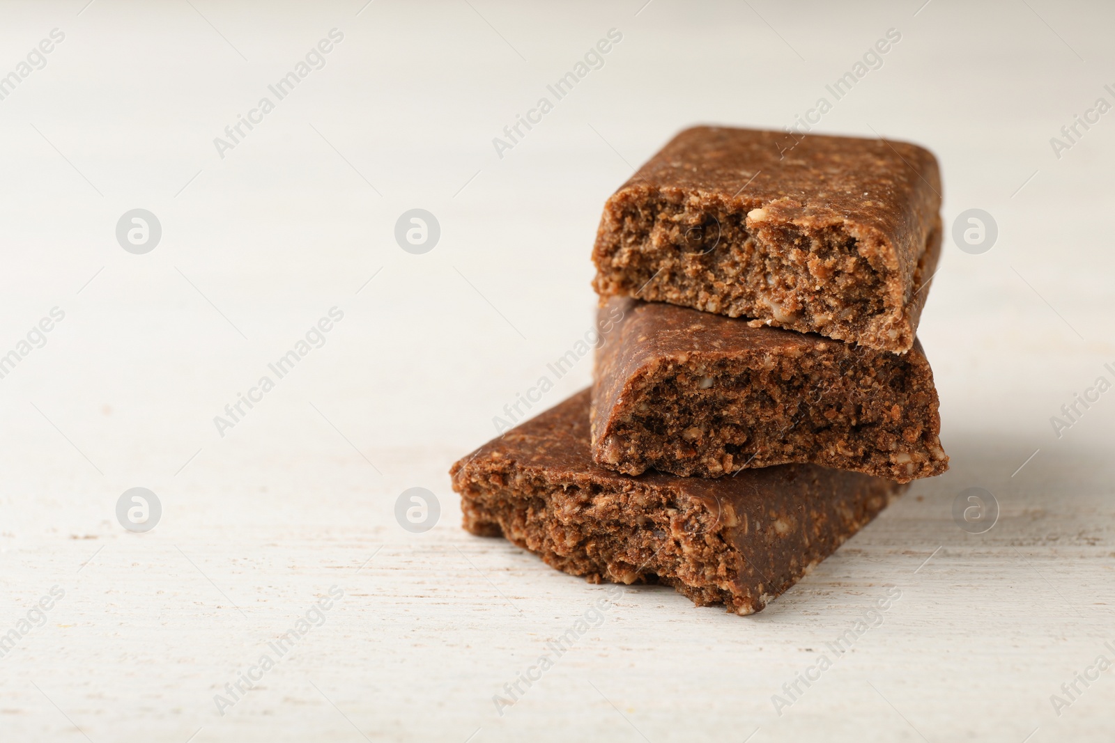 Photo of Pieces of tasty protein bar on white table. Space for text