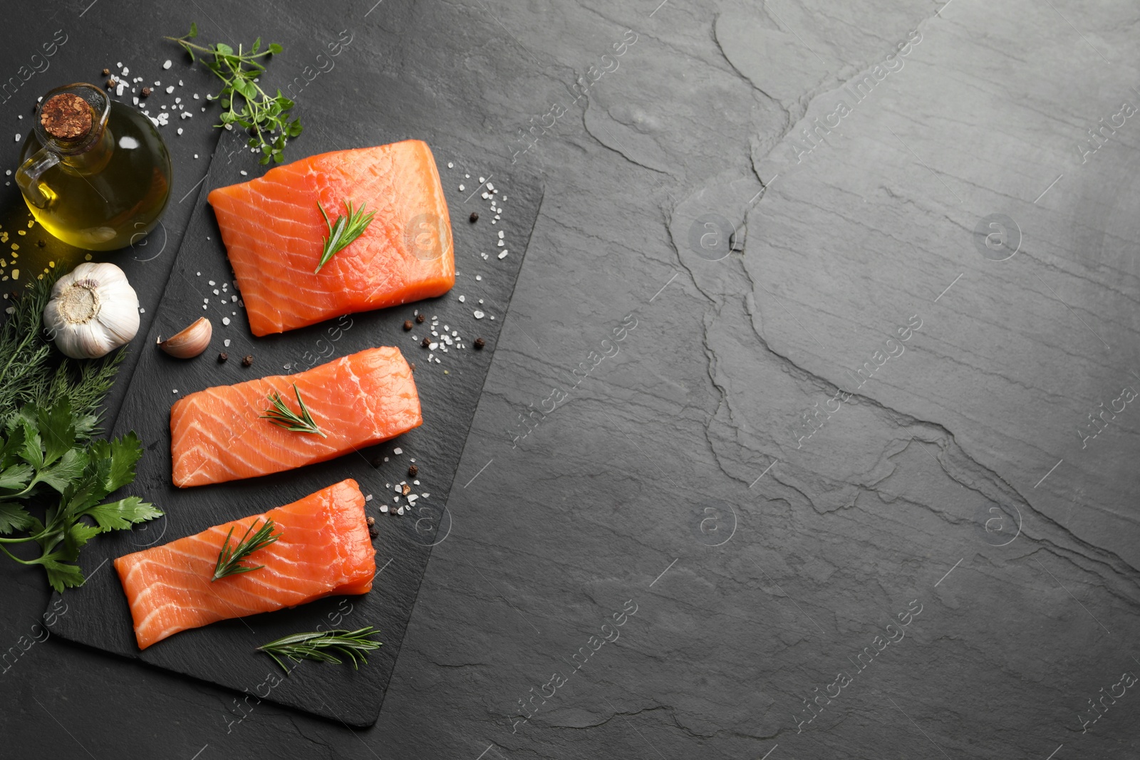 Photo of Fresh raw salmon and spices on black table, flat lay. Space for text