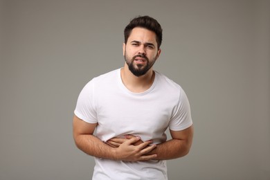 Photo of Young man suffering from stomach pain on light grey background