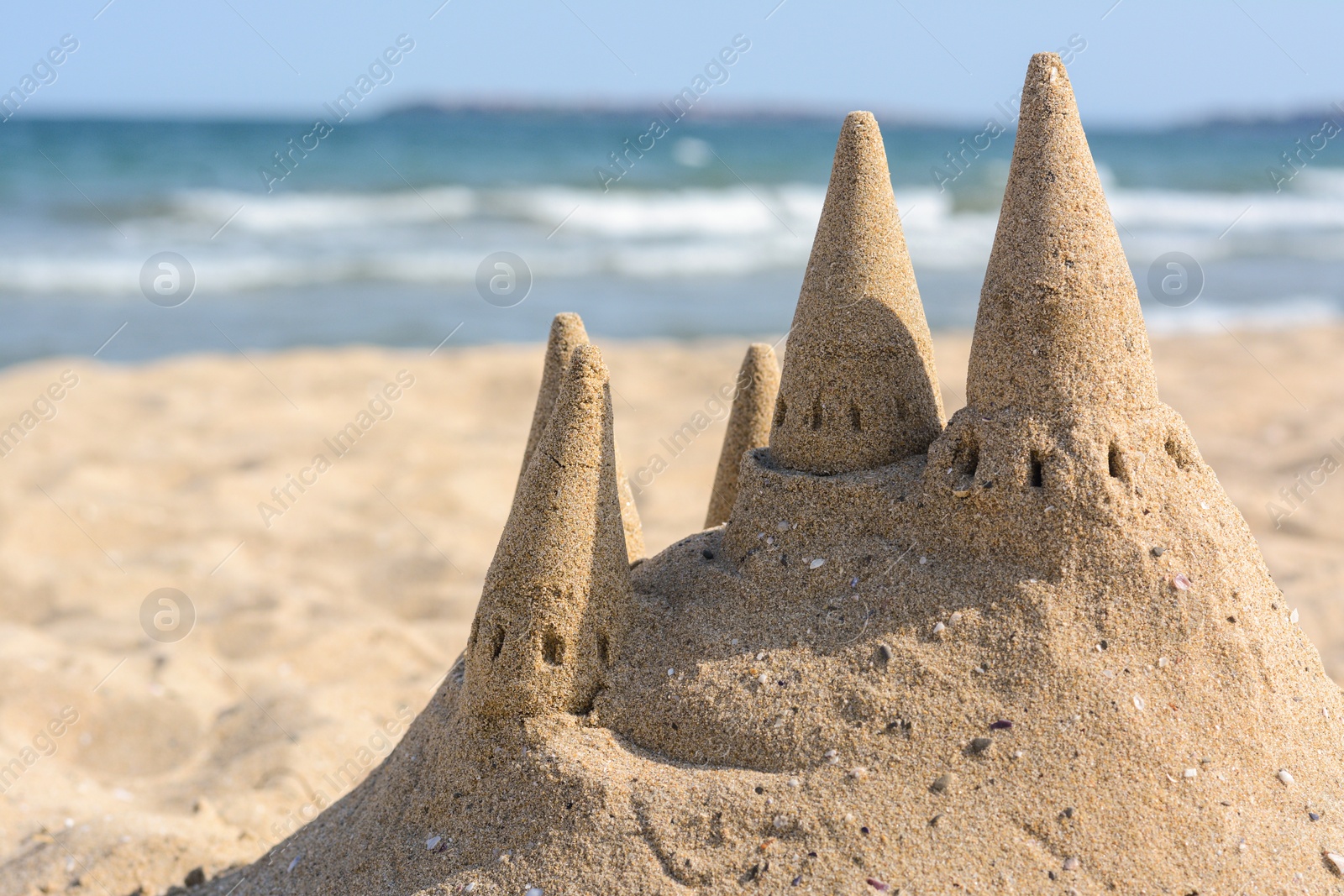 Photo of Beach with sand castle near sea on sunny day. Space for text