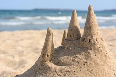 Photo of Beach with sand castle near sea on sunny day. Space for text