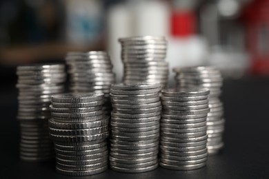Photo of Many coins stacked on black table against blurred background