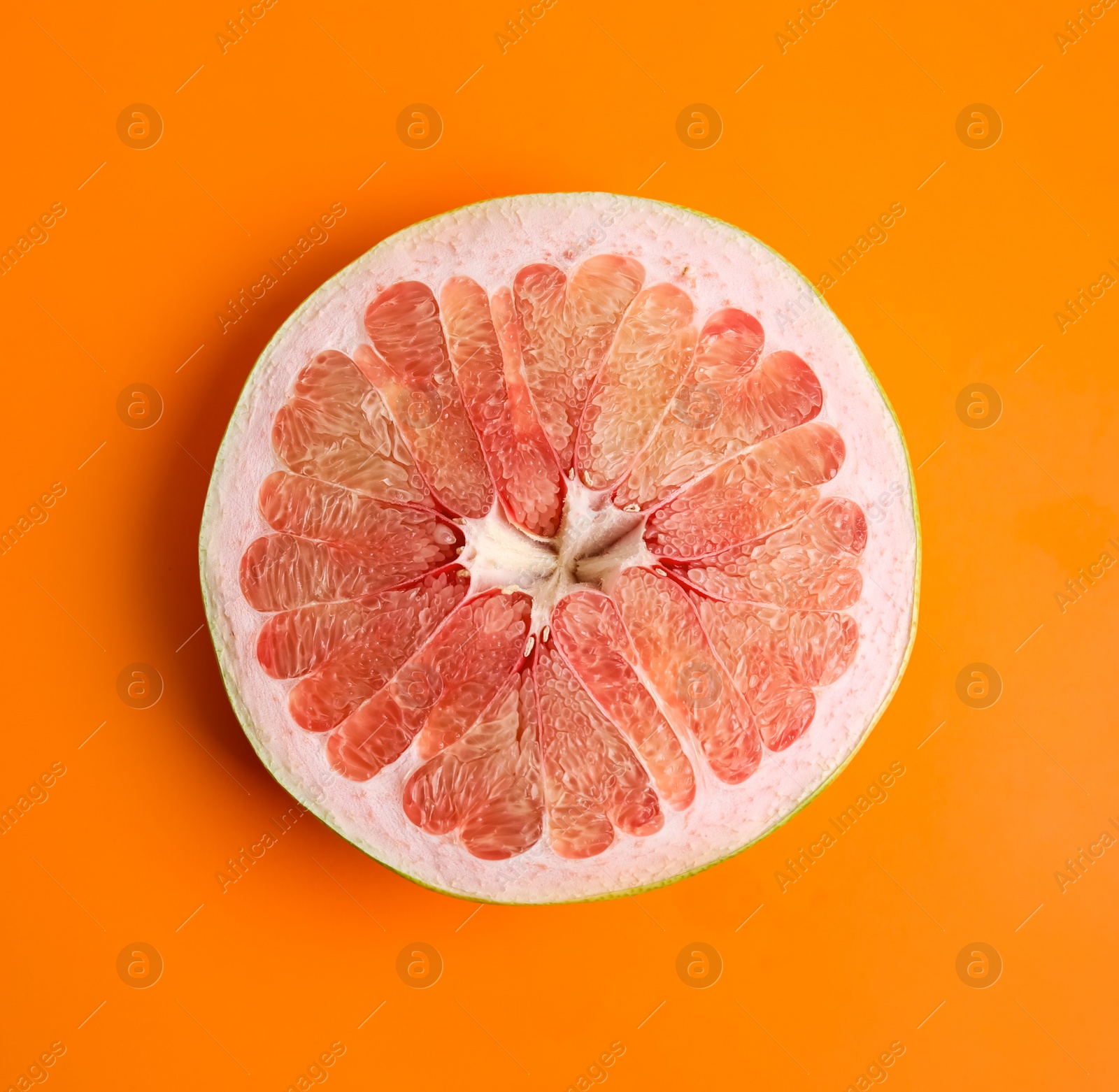 Photo of Fresh cut pomelo fruit on orange background, top view