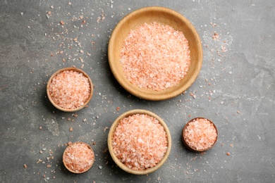 Photo of Pink himalayan salt in wooden bowls on grey table, flat lay