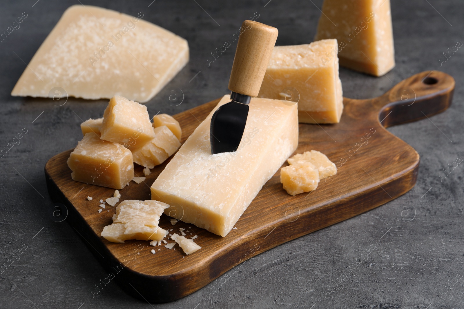 Photo of Parmesan cheese with knife on grey table