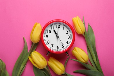 Photo of Red alarm clock and beautiful tulips on pink background, flat lay. Spring time
