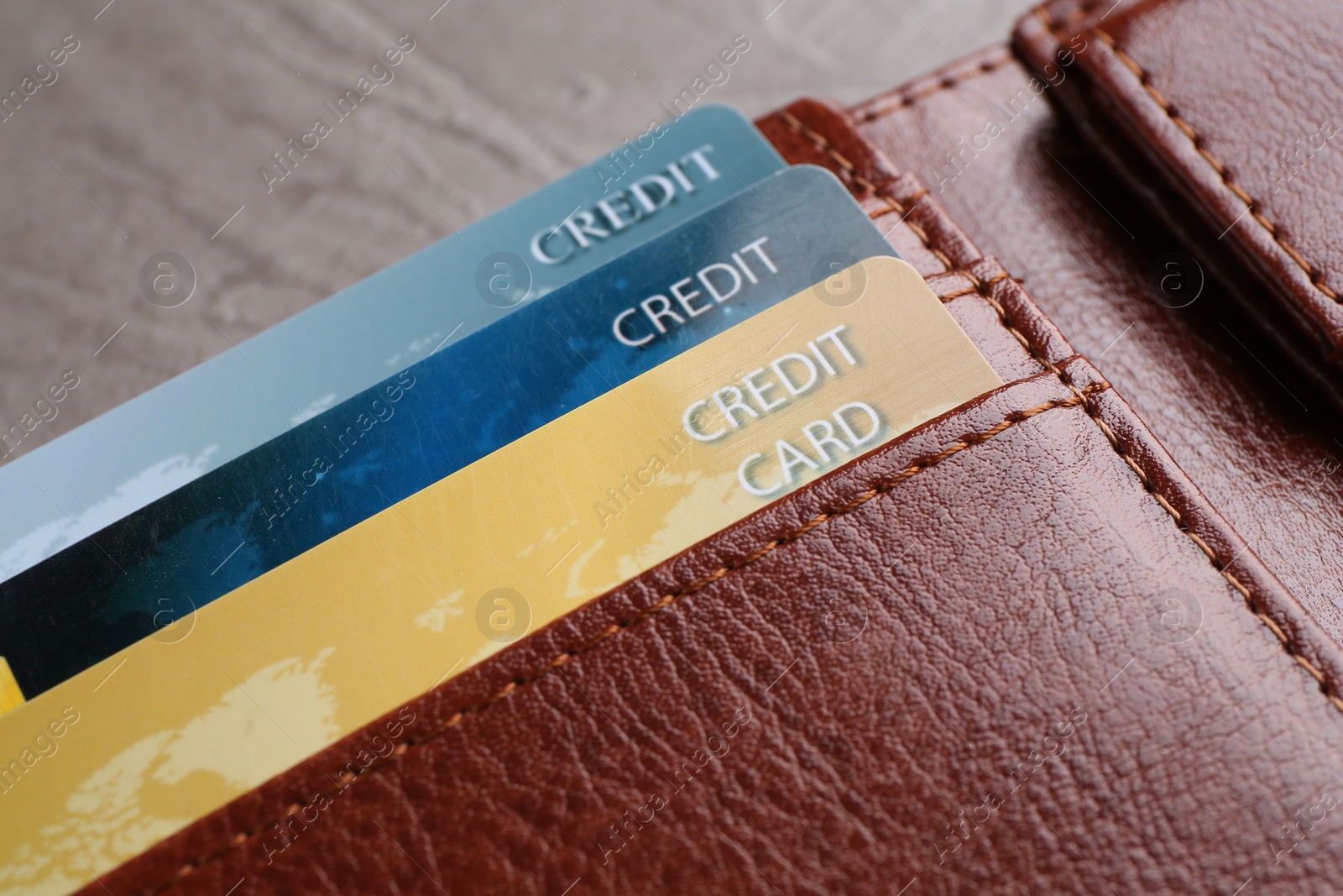 Photo of Credit cards in leather wallet on grey table, closeup