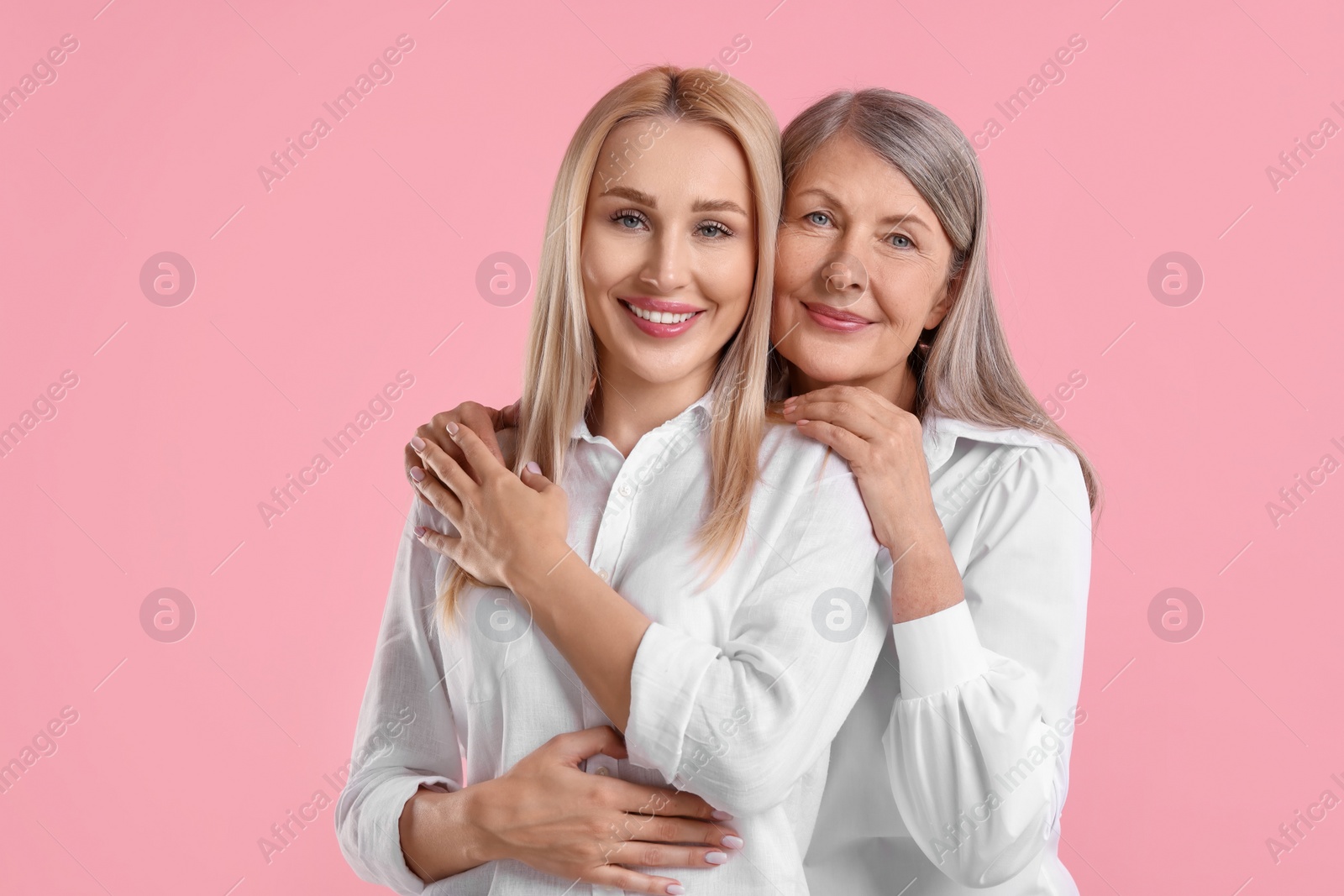 Photo of Family portrait of young woman and her mother on pink background