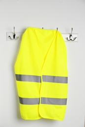 Reflective vest hanging on white wall. Safety equipment