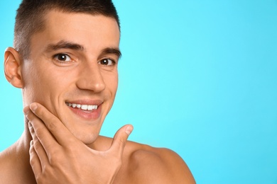 Handsome young man after shaving on light blue background, space for text