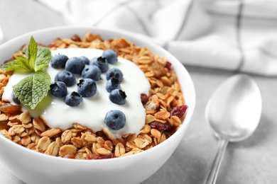 Delicious yogurt with granola and blueberries served on grey table, closeup