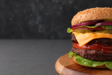 Photo of Tasty cheeseburger with patties on grey table, closeup. Space for text
