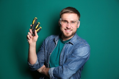 Young working man with screwdrivers on green background